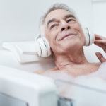 oudere man met koptelefoon op in bad