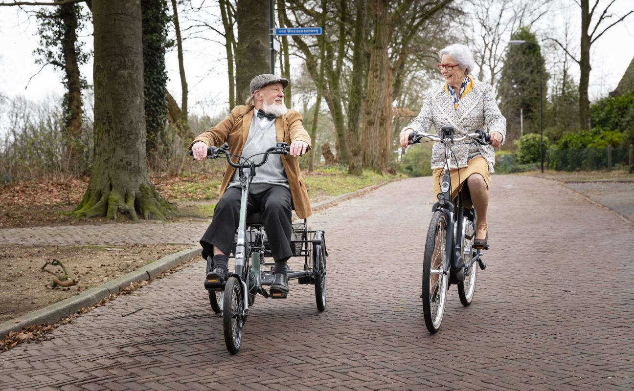 oudere man op driewielfiets en vrouw op tweewiel fiets