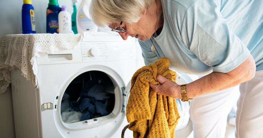 oudere vrouw doet was in de wasmachine