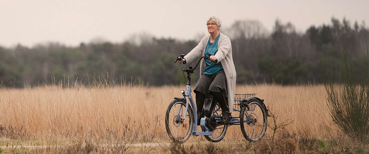 Vrouw fietst door de veluwe op haar elektrische driewieler