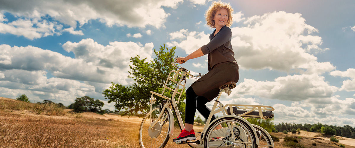 Vrouw fiets op driewielfiets in de zon