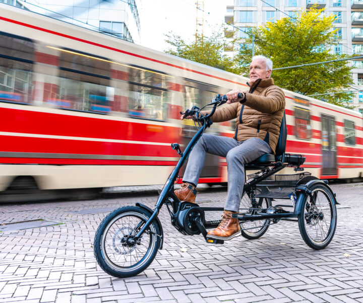 oudere man fiets op driewielfiets in stad naast tram